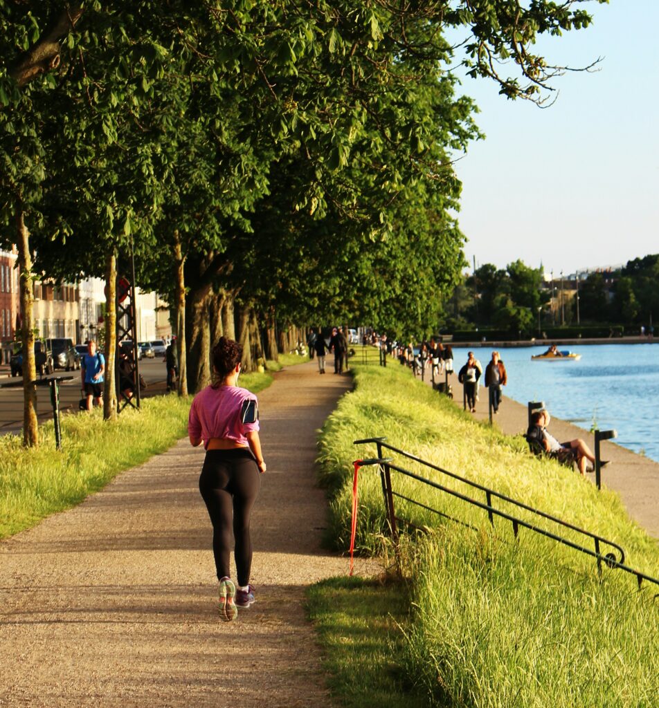 Läuferin joggt auf einem Uferweg entlang eines Sees bei Sonnenuntergang